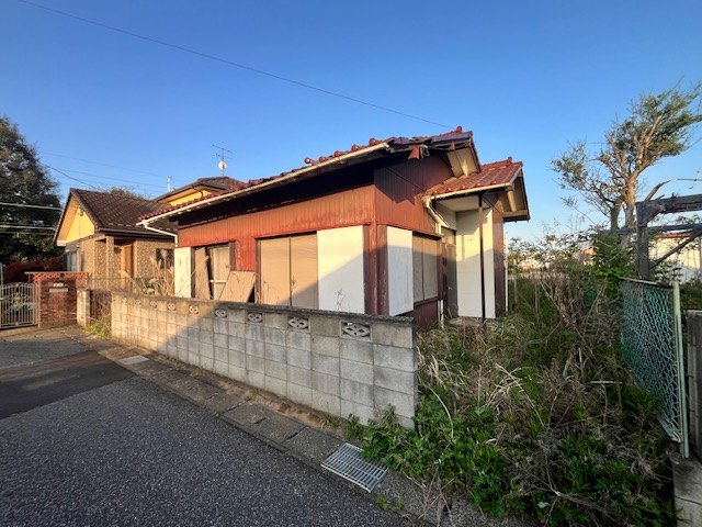 草に覆われた、使われなくなった空き家の外観